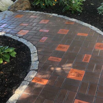 Custom brick walkway through a flower garden with memorial bricks included in the pattern