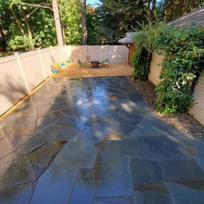 Fenced yard with hardscape flagstone and gravel areas created by Willie C. & Sons Landscaping.