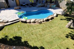Stone patio and pool surround built for a residential backyard by Willie C. & Sons Landscaping.